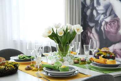 Festive Easter table setting with beautiful white tulips and eggs indoors