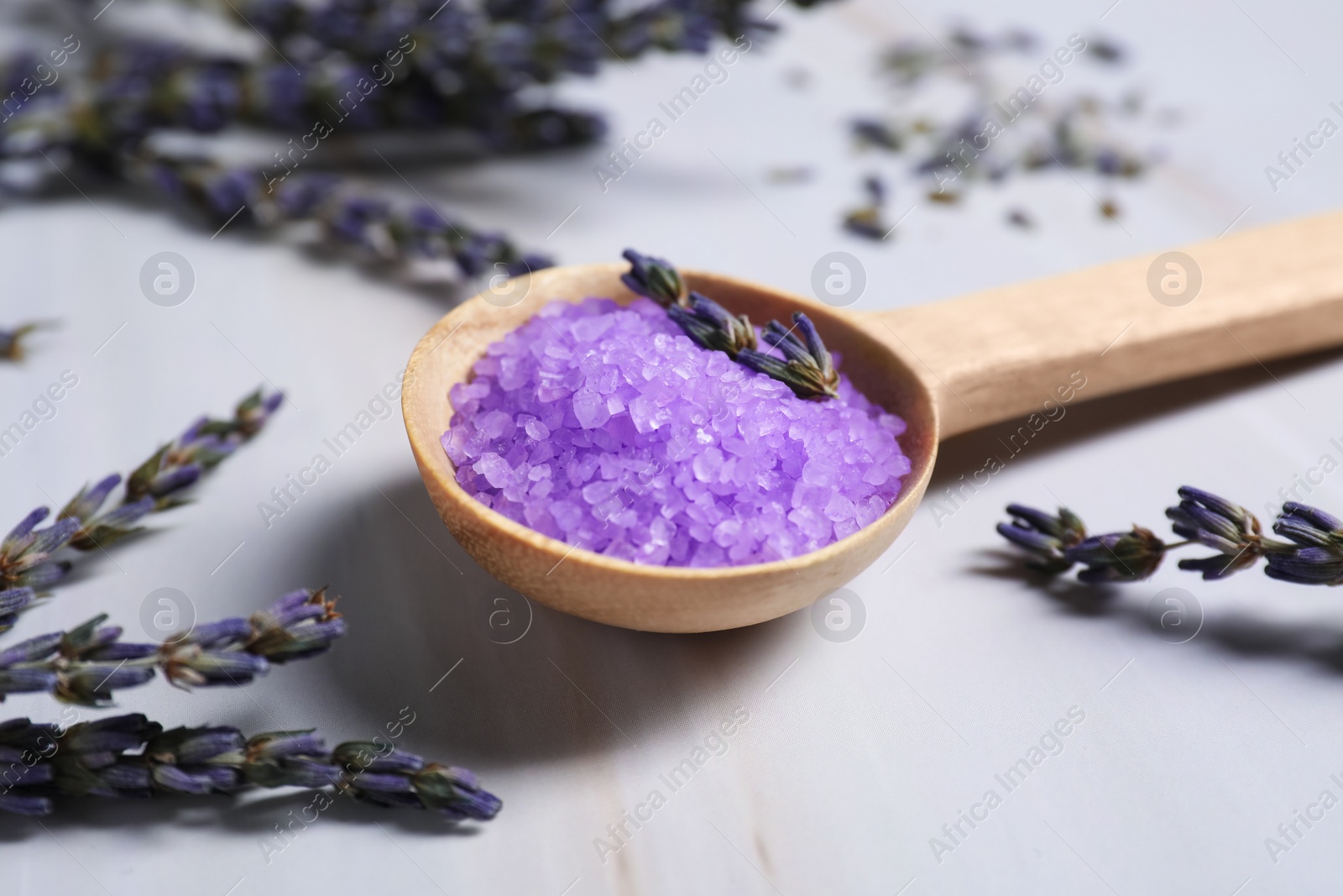 Photo of Spoon with purple sea salt and lavender on wooden table, closeup
