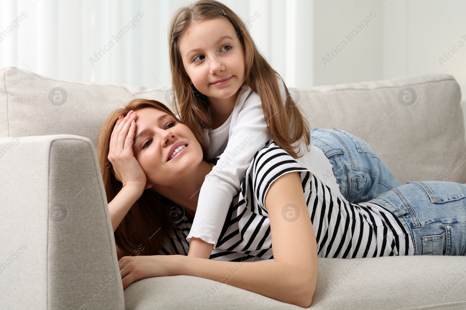 Photo of Happy mother with her cute daughter spending time together on sofa at home