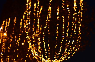 Blurred view of street with beautiful lights on trees at night. Bokeh effect