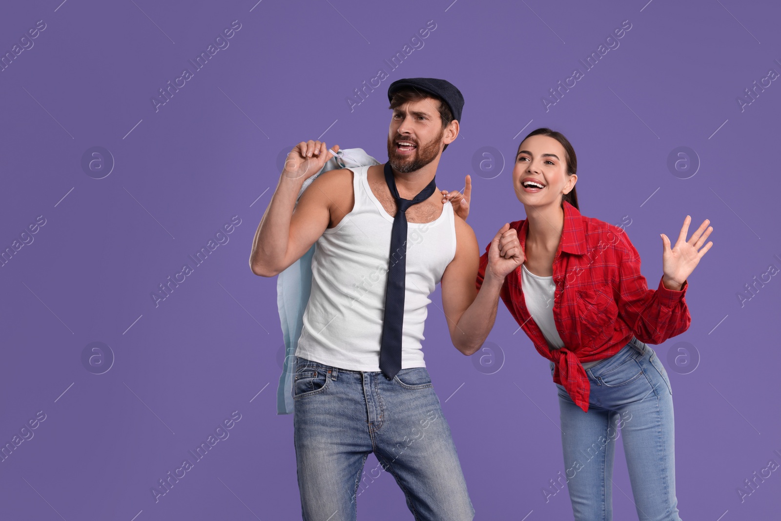 Photo of Happy couple dancing together on violet background, space for text