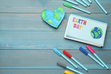 Photo of Happy Earth Day. Flat lay composition with notebook and markers on turquoise wooden table, space for text