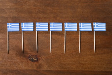 Small paper flags of Greece on wooden table, flat lay