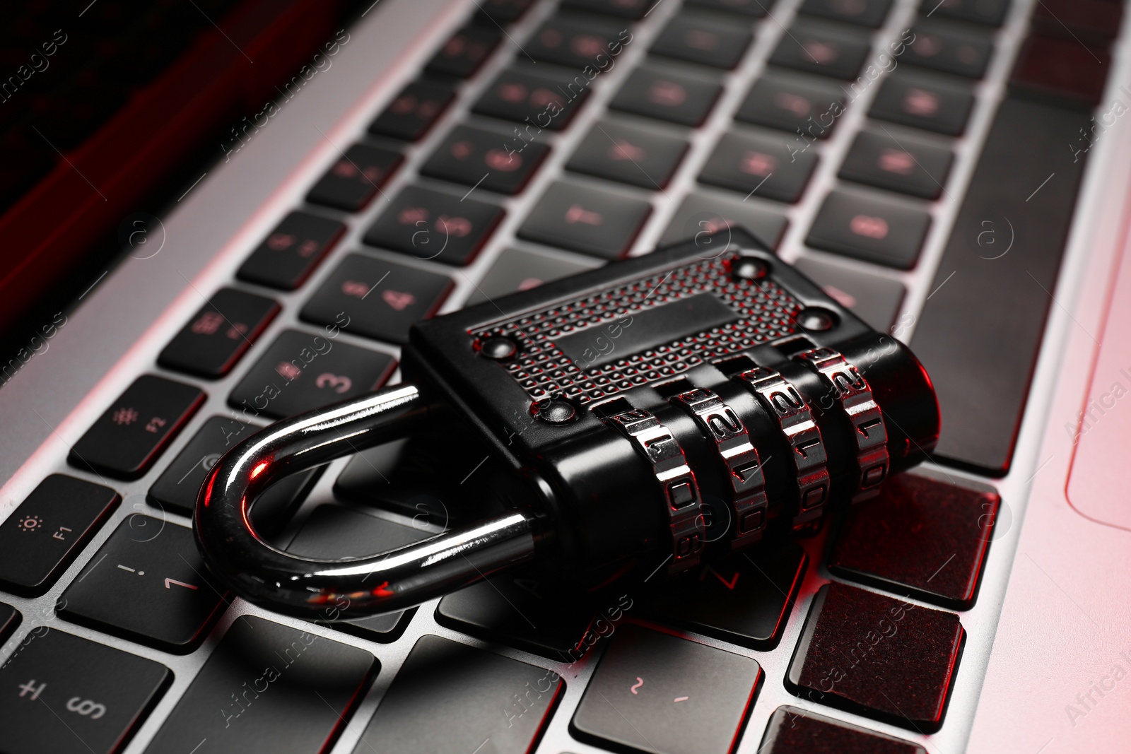 Photo of Cyber security. Metal combination padlock on laptop, closeup