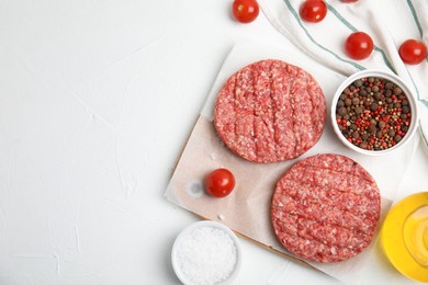 Photo of Raw hamburger patties with spices and tomatoes on white table, flat lay. Space for text