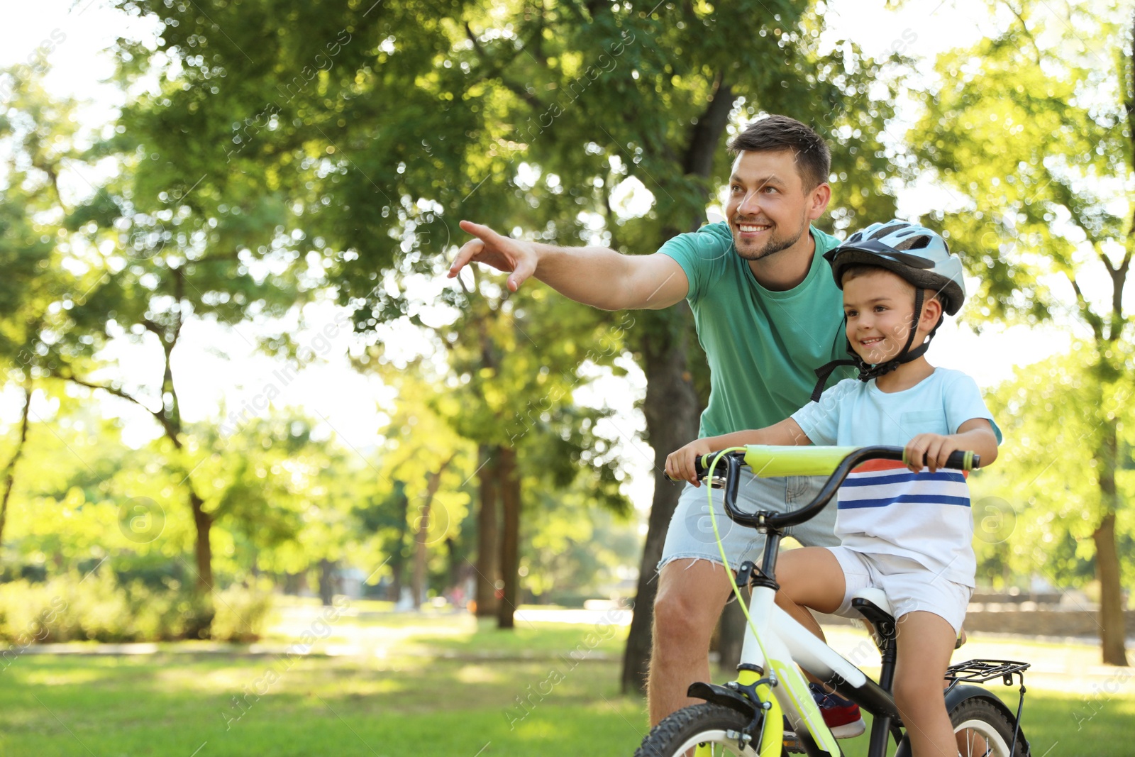 Photo of Happy father teaching his son to ride bicycle in park