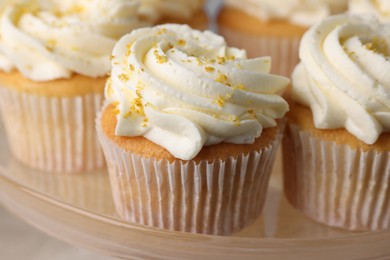 Photo of Delicious cupcakes with white cream and lemon zest on plate, closeup