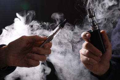 Photo of People with electronic cigarettes on black background, closeup