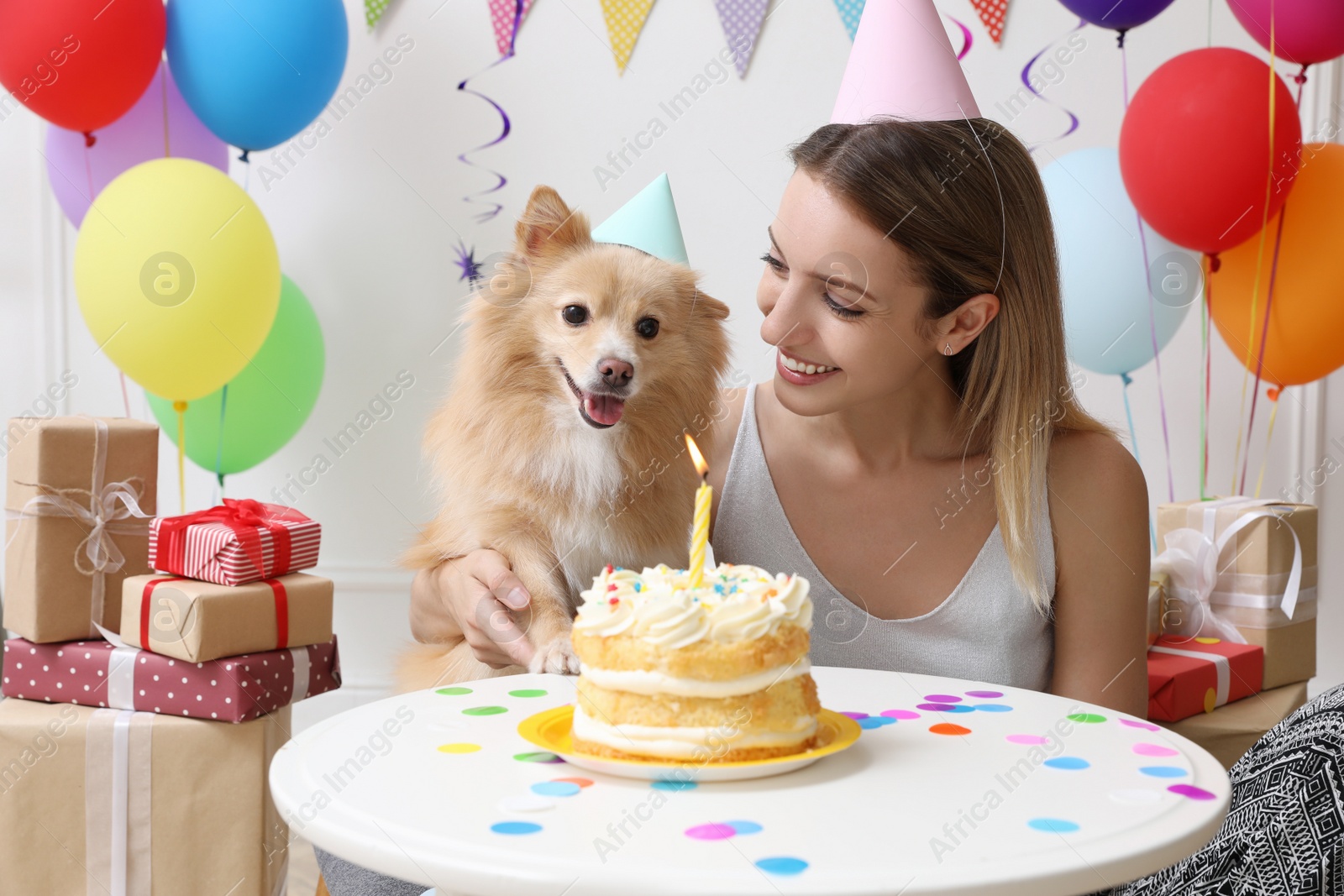 Photo of Happy woman celebrating her pet's birthday in decorated room