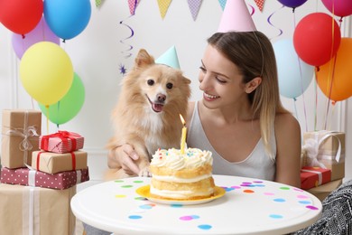 Happy woman celebrating her pet's birthday in decorated room