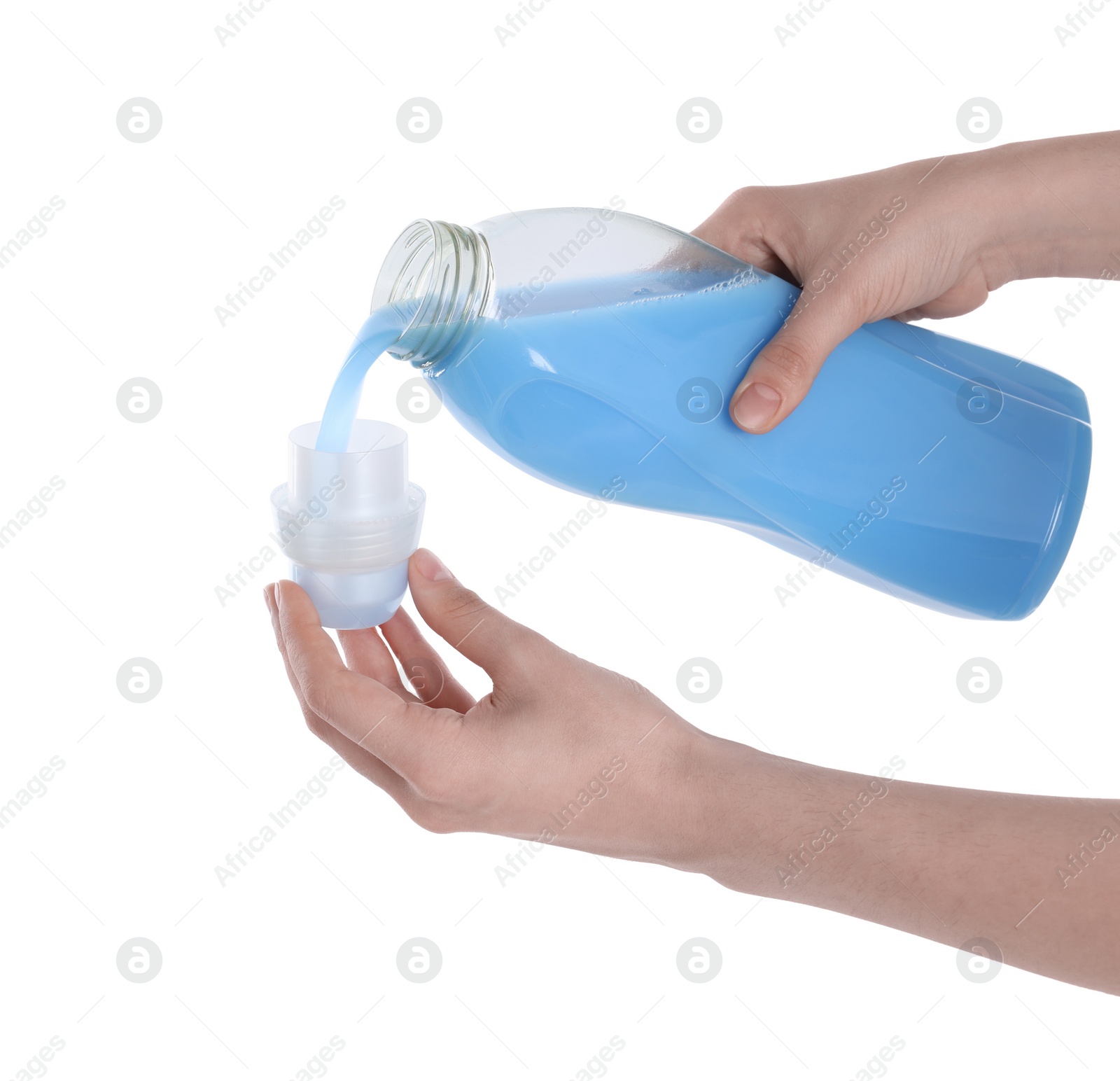 Photo of Woman pouring fabric softener from bottle into cap on white background, closeup