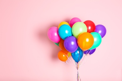 Photo of Bunch of bright balloons on color background with space for design