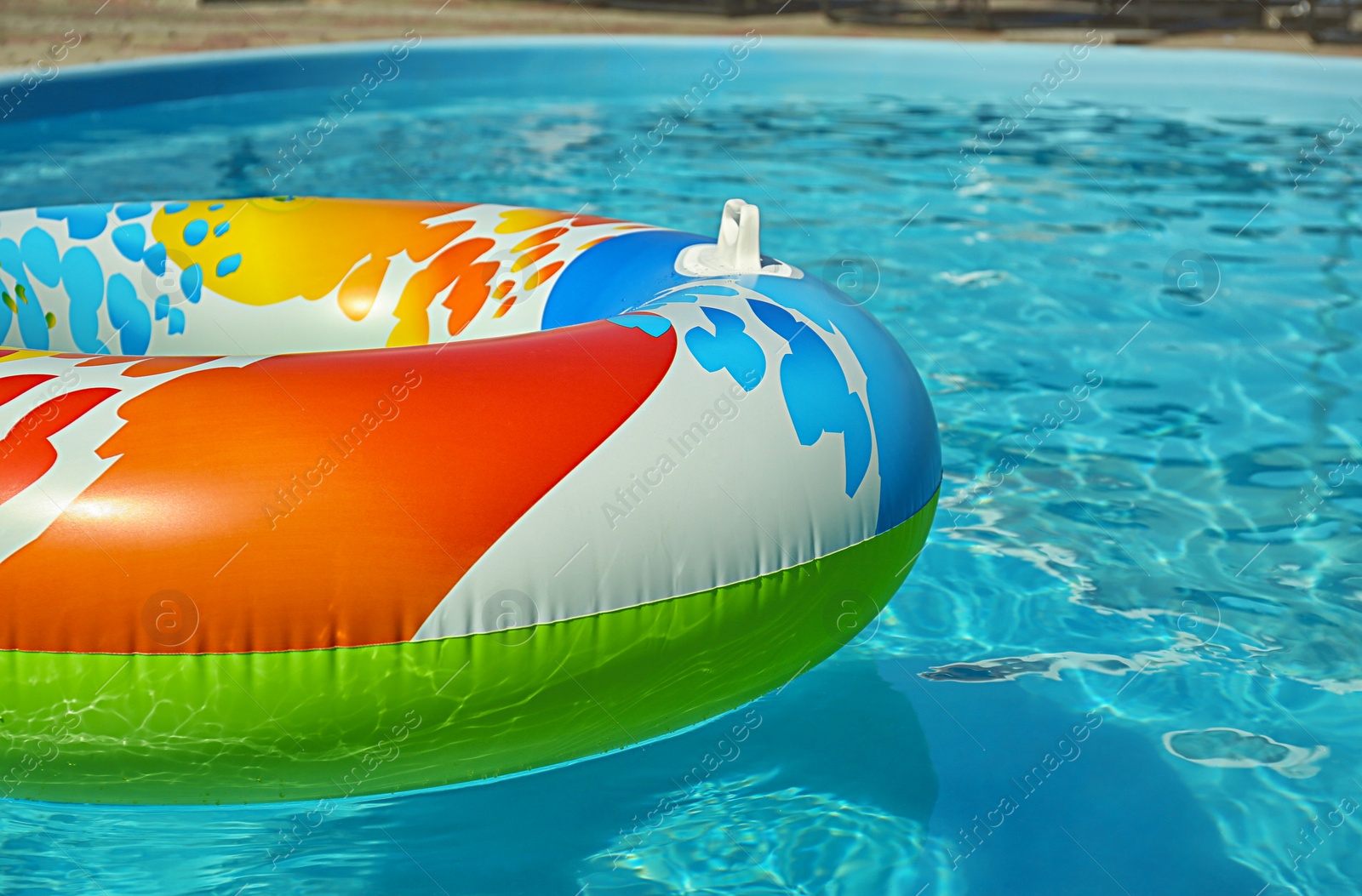 Photo of Bright inflatable ring floating in swimming pool on sunny day. Space for text