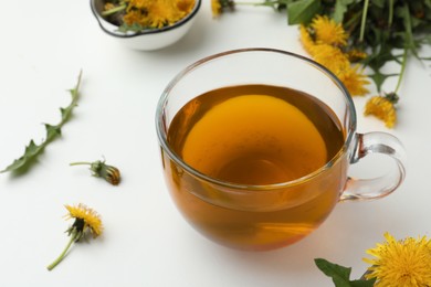 Delicious fresh tea and beautiful dandelion flowers on white background