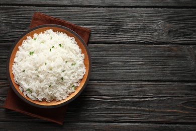 Plate of tasty cooked rice on wooden background, top view. Space for text