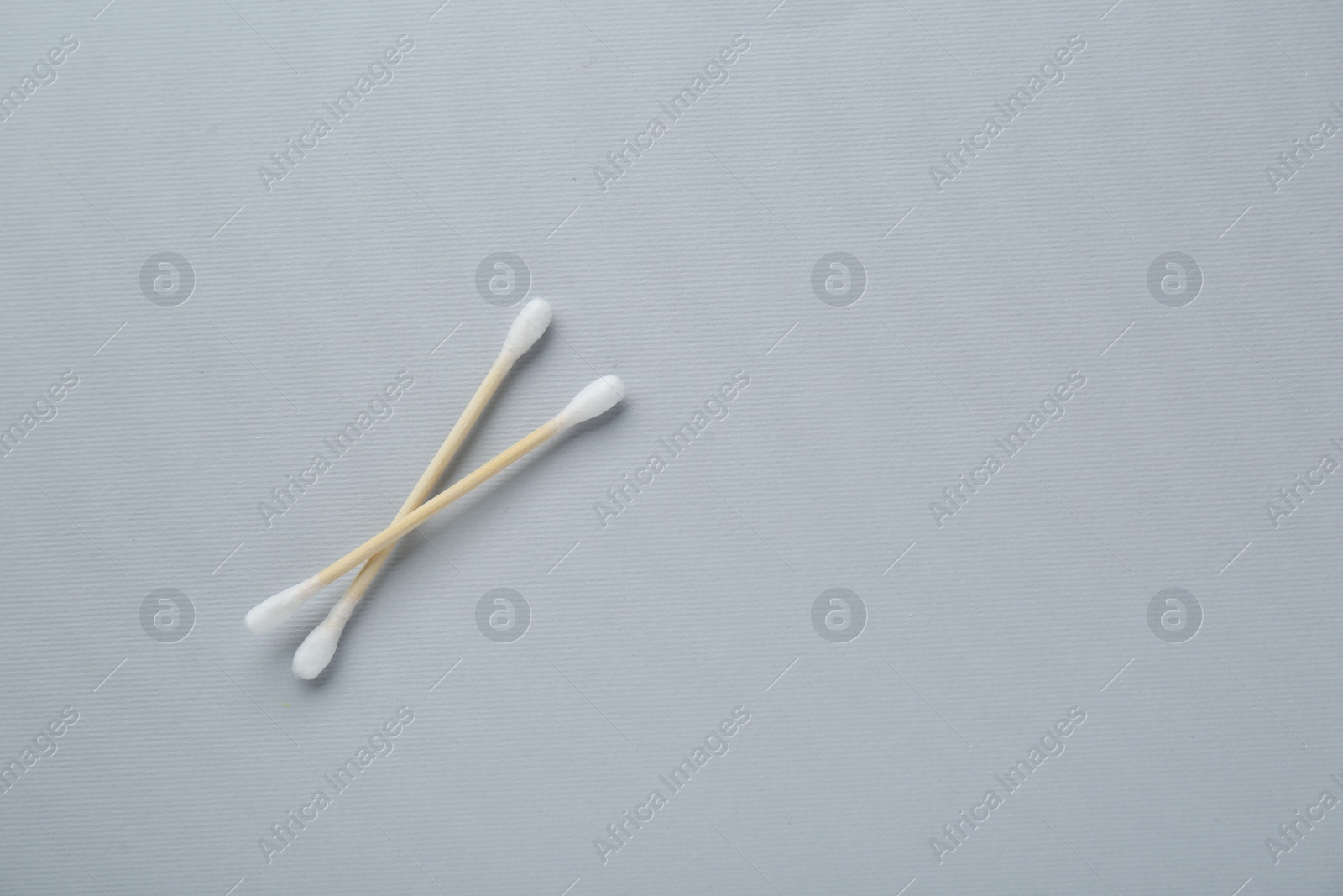 Photo of Two wooden cotton buds on light grey background, flat lay. Space for text