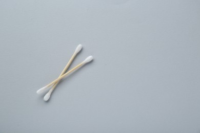 Photo of Two wooden cotton buds on light grey background, flat lay. Space for text