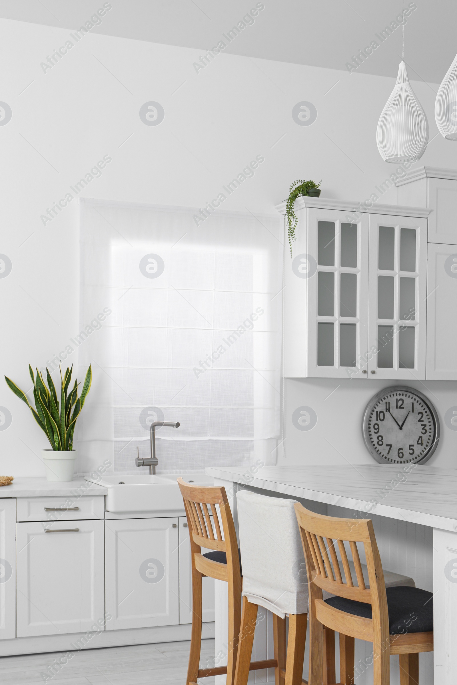 Photo of Stylish white marble table with chairs in kitchen. Interior design