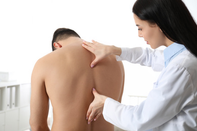 Photo of Professional orthopedist examining man in medical office