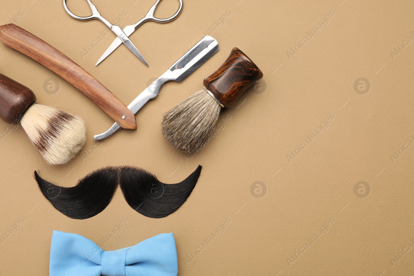 Photo of Artificial moustache and barber tools on beige background, flat lay. Space for text