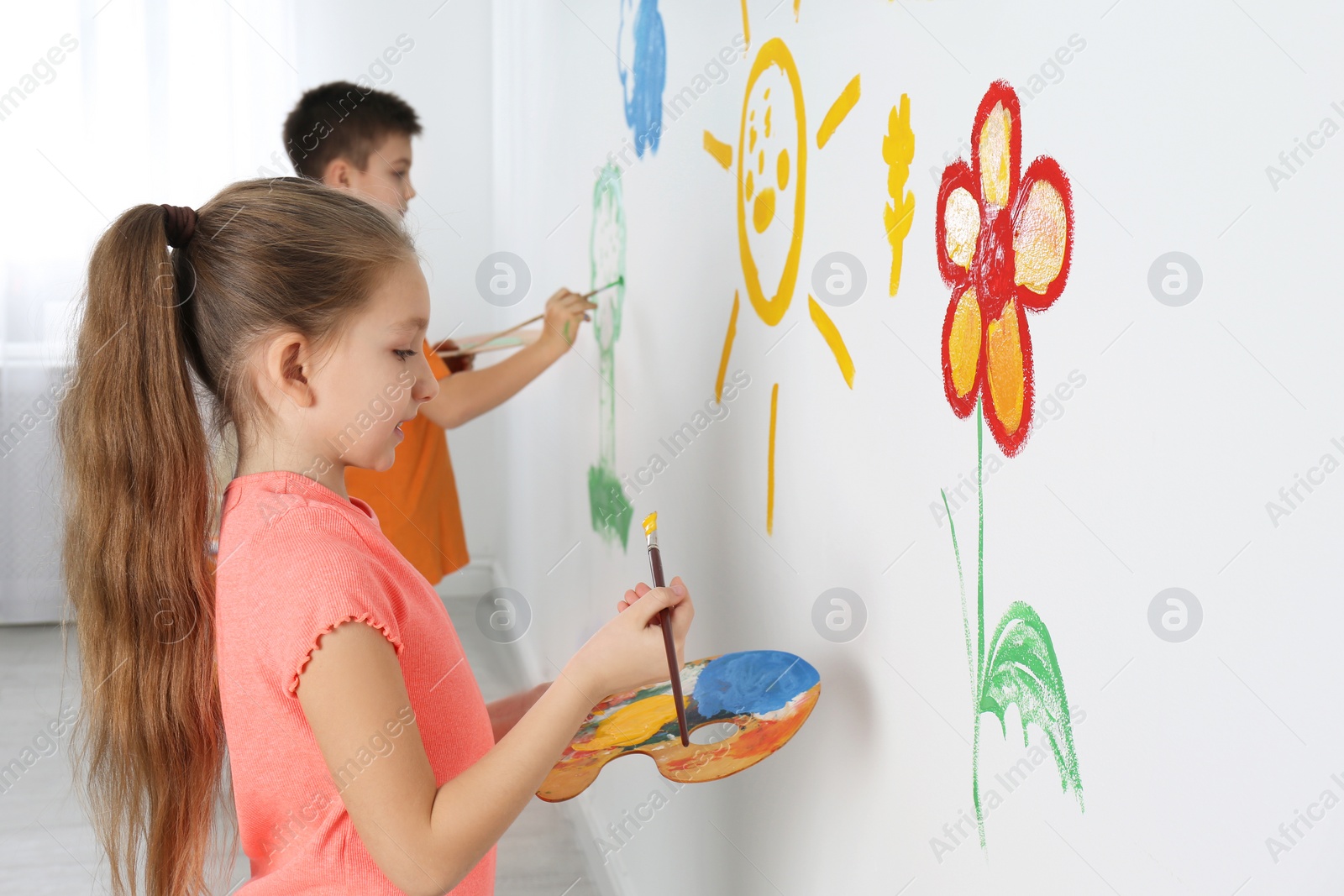 Photo of Little children painting on white wall indoors