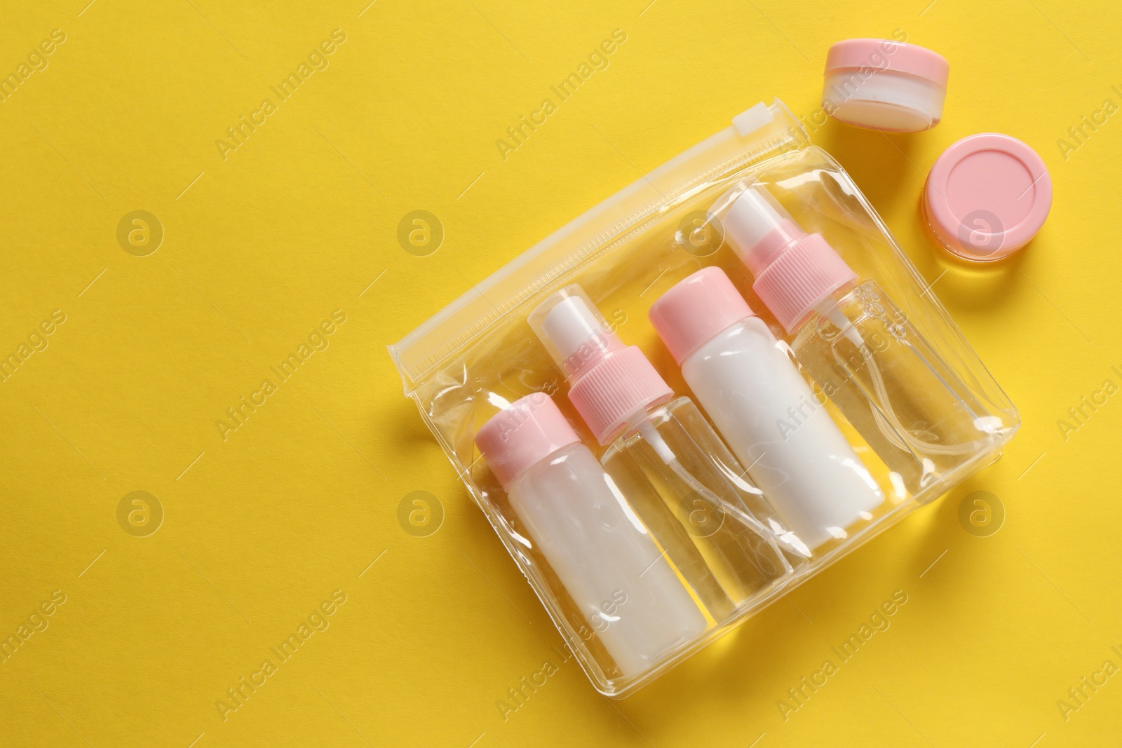 Photo of Plastic bag with cosmetic travel kit on yellow background, flat lay. Space for text