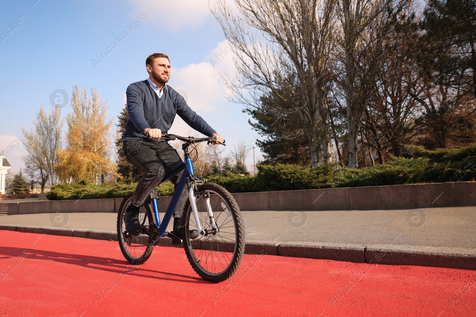 Photo of Happy handsome man riding bicycle on lane in city