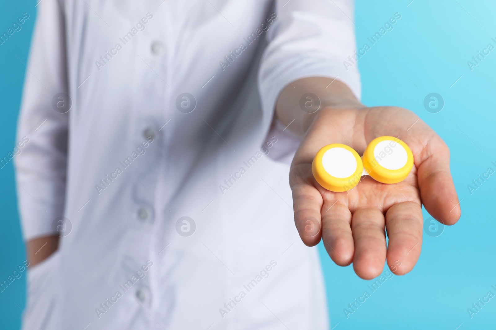 Photo of Female doctor holding contact lens case on color background, closeup. Medical object