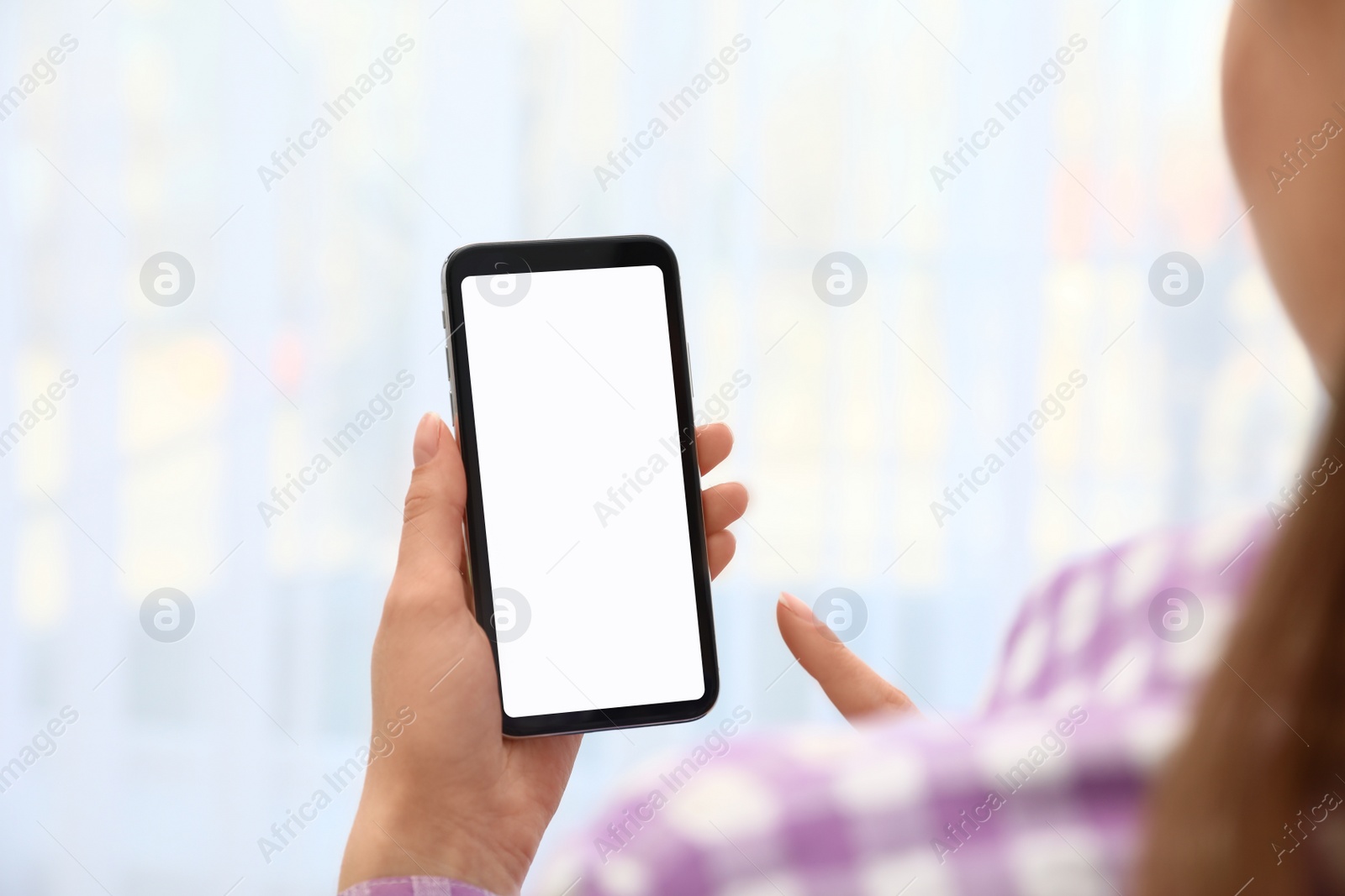 Photo of Woman holding smartphone with blank screen on blurred background, closeup of hands. Space for text