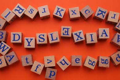 Wooden cubes with word Dyslexia on orange background, flat lay