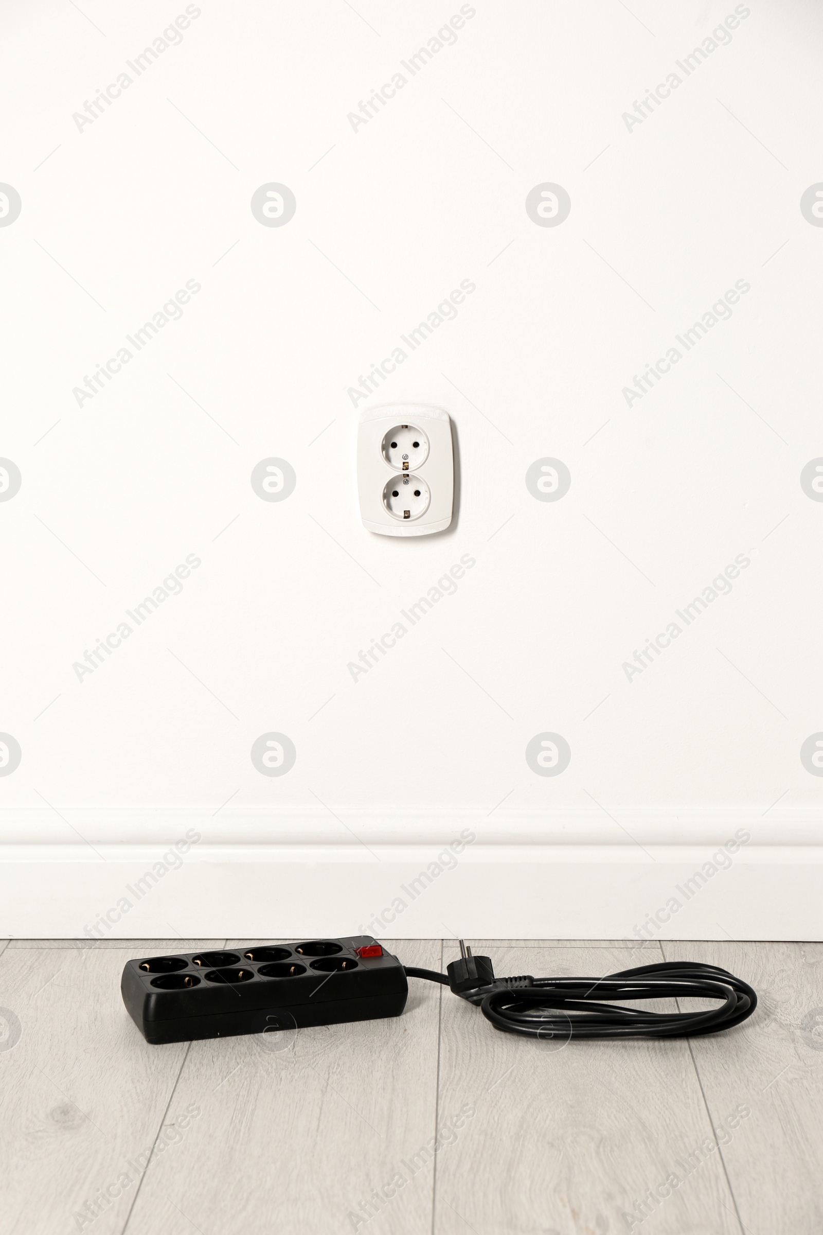 Photo of Extension cord near wall indoors, space for text. Electrician's professional equipment