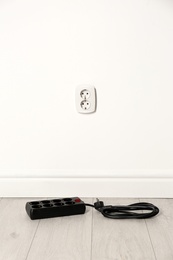 Extension cord near wall indoors, space for text. Electrician's professional equipment