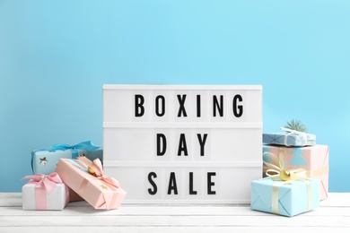 Composition with Boxing Day Sale sign and Christmas gifts on white table against light blue background