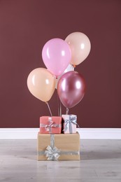 Many gift boxes and balloons near brown wall