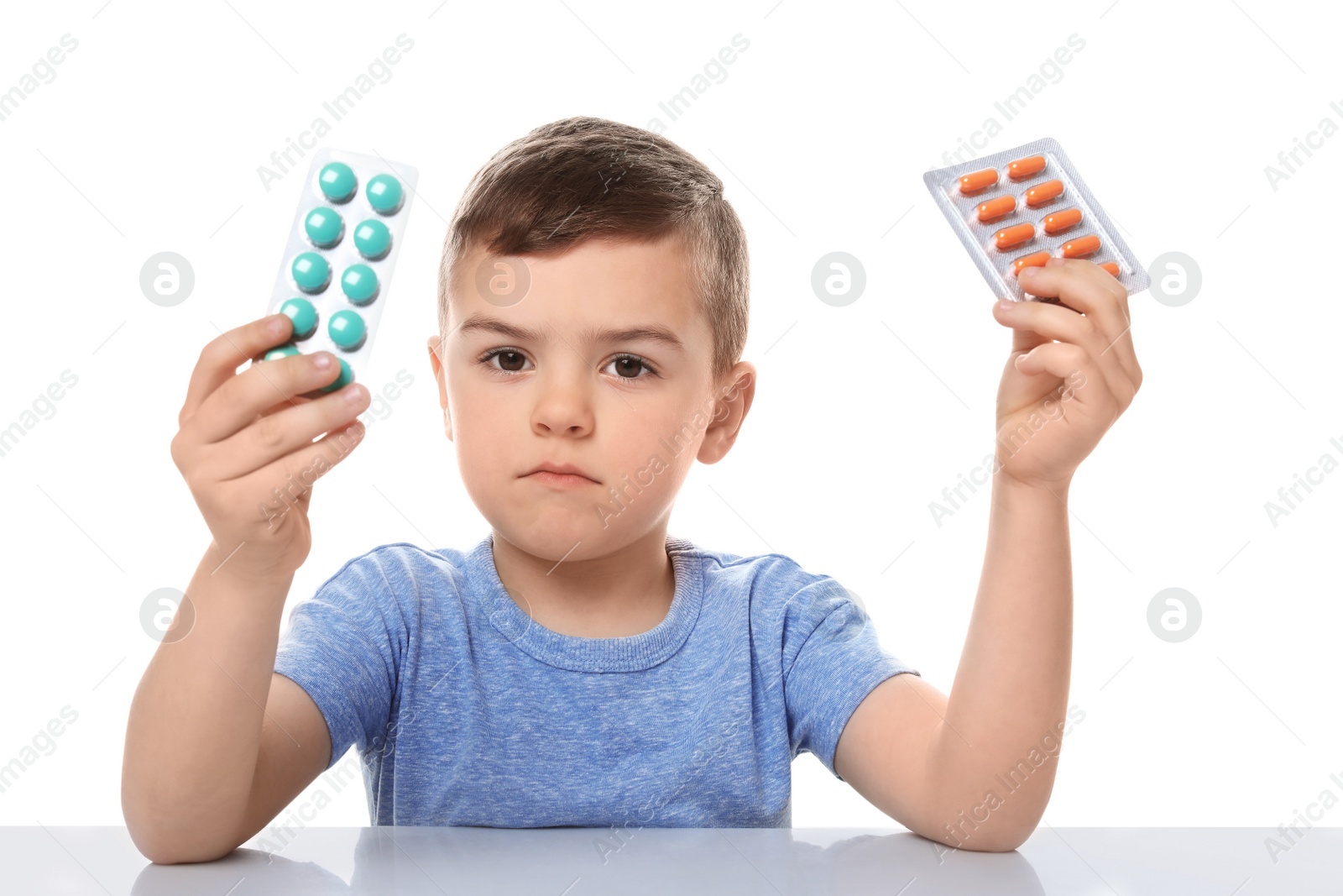 Photo of Little child with different pills on white background. Household danger