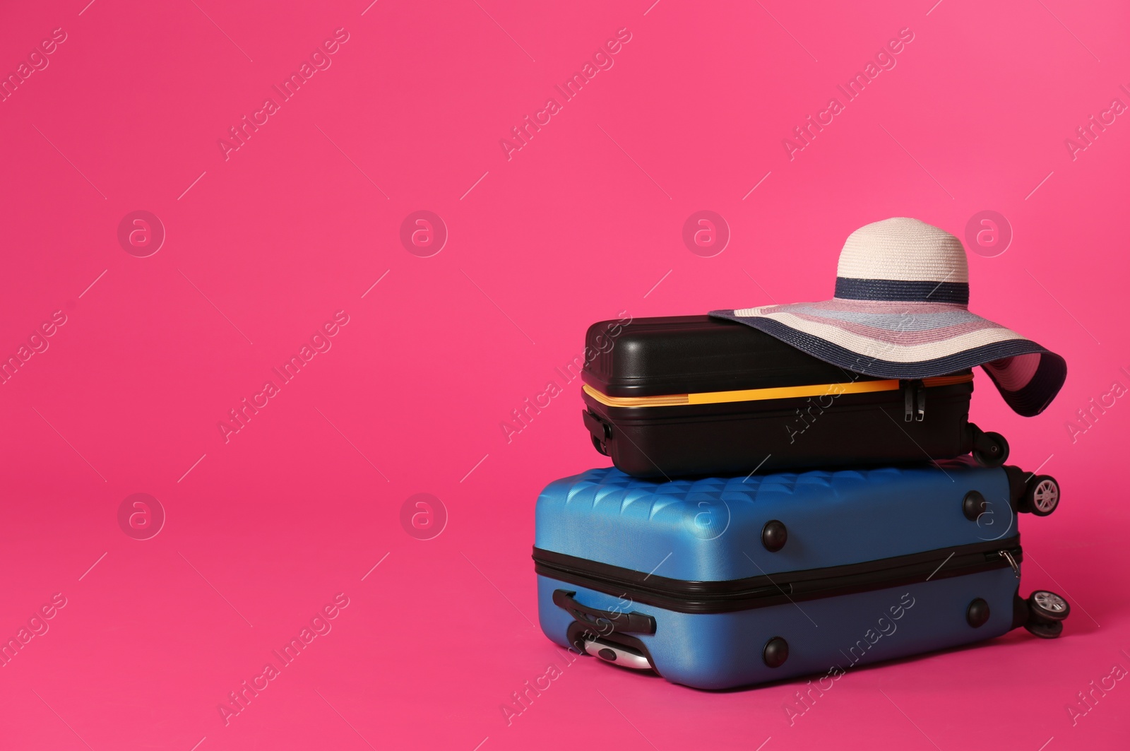 Photo of Stylish suitcases with hat on color background. Space for text