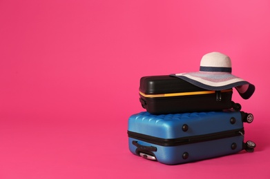 Stylish suitcases with hat on color background. Space for text