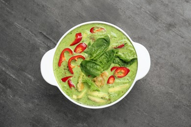 Saucepan with delicious green curry chicken soup on light grey table, top view