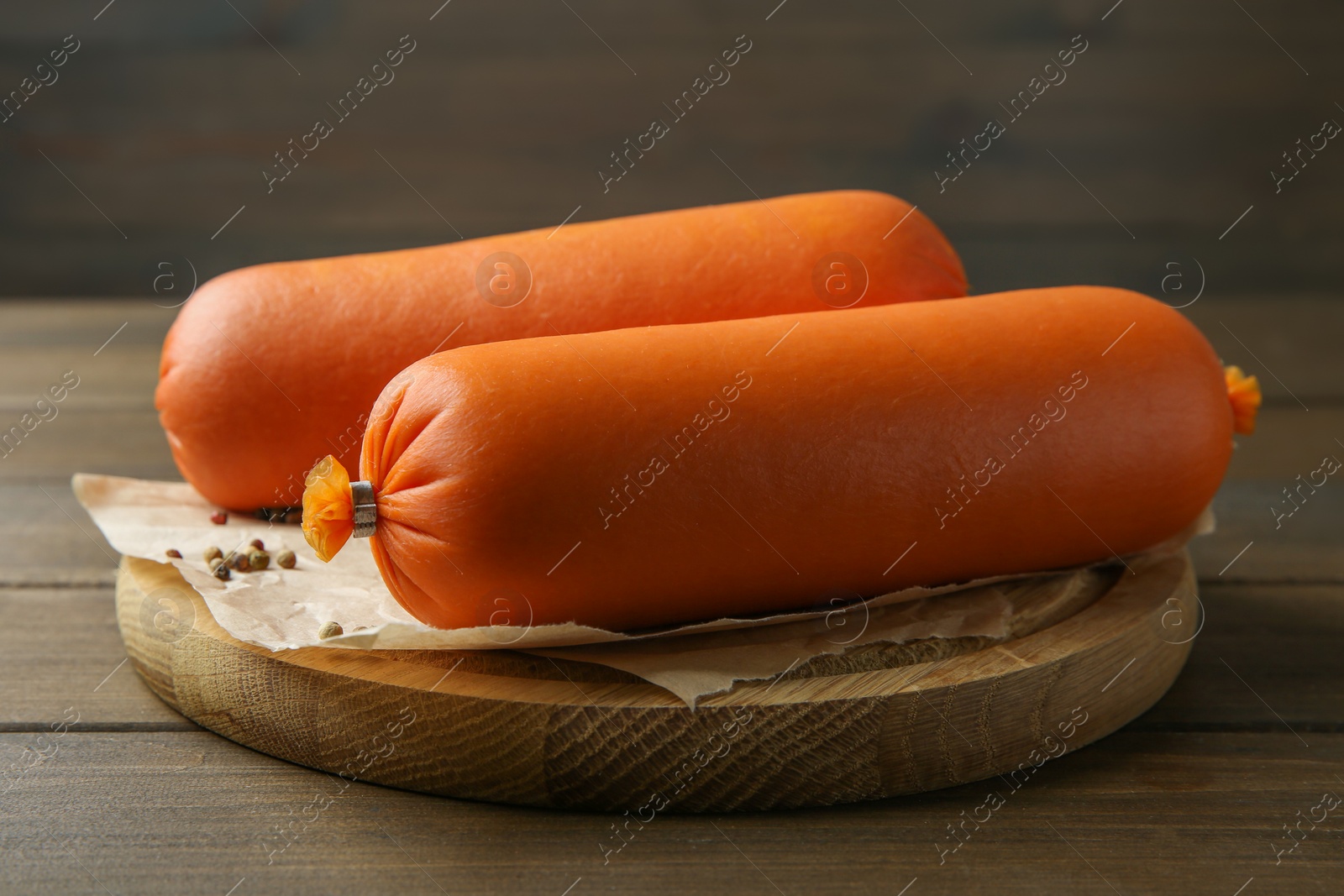 Photo of Board with tasty boiled sausages on wooden table, closeup