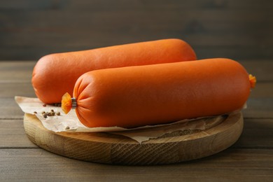 Photo of Board with tasty boiled sausages on wooden table, closeup