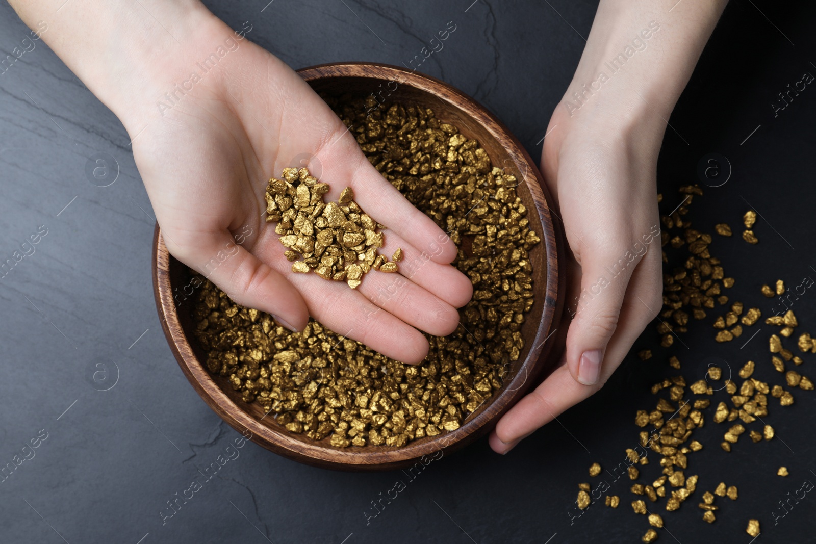 Photo of Woman with gold nuggets at black table, top view