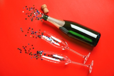 Photo of Creative flat lay composition with bottle of champagne and glasses on color background