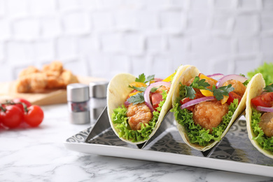 Photo of Yummy fish tacos served on white marble table