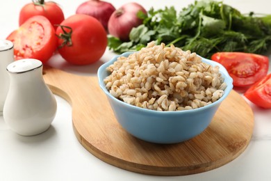 Photo of Delicious pearl barley in bowl served on white table