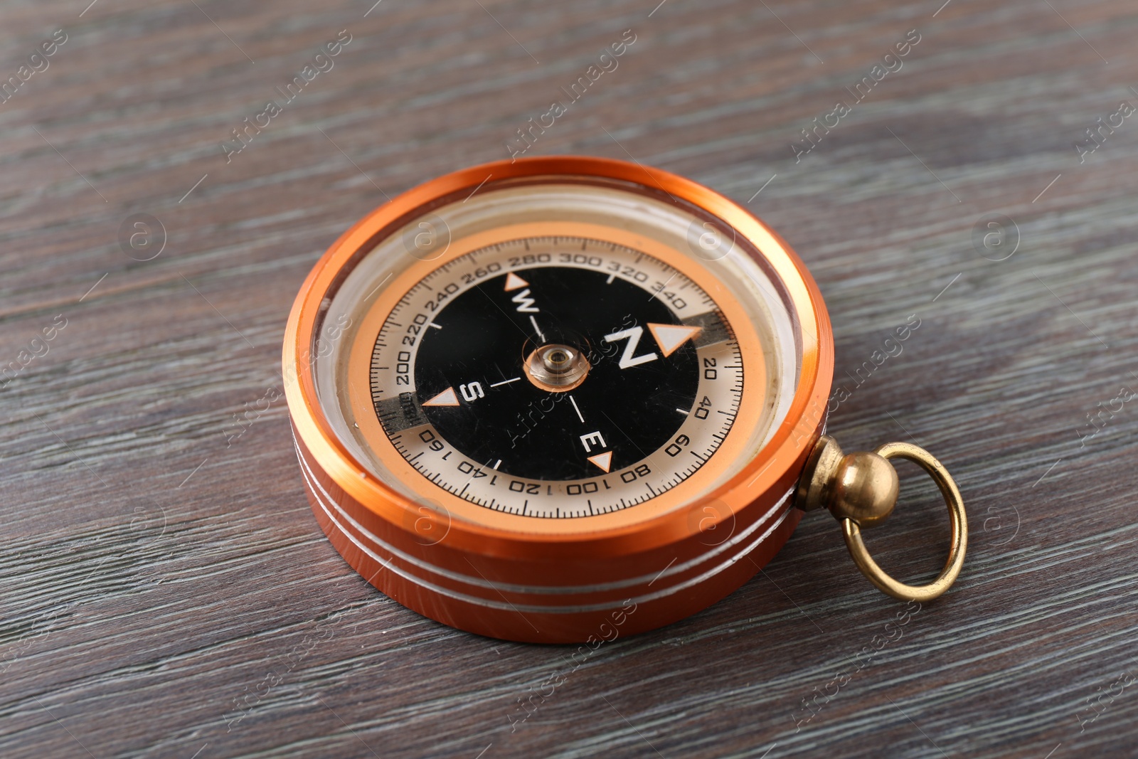 Photo of One compass on wooden table, closeup. Tourist equipment