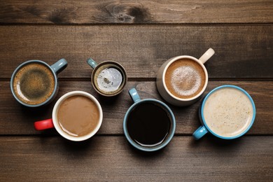 Photo of Cups of fresh aromatic coffee on wooden table, flat lay