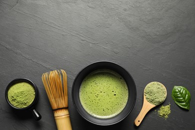 Cup of fresh matcha tea, spoon, bamboo whisk and green powder on black table, flat lay. Space for text