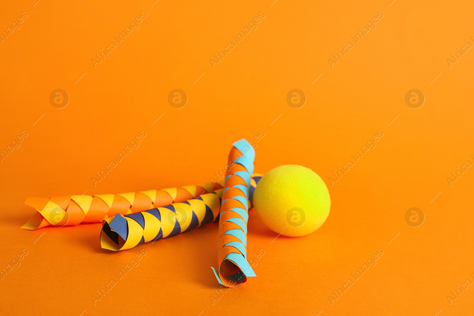 Photo of Chinese finger traps and clown nose on orange background