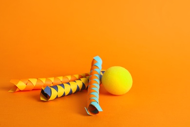 Chinese finger traps and clown nose on orange background