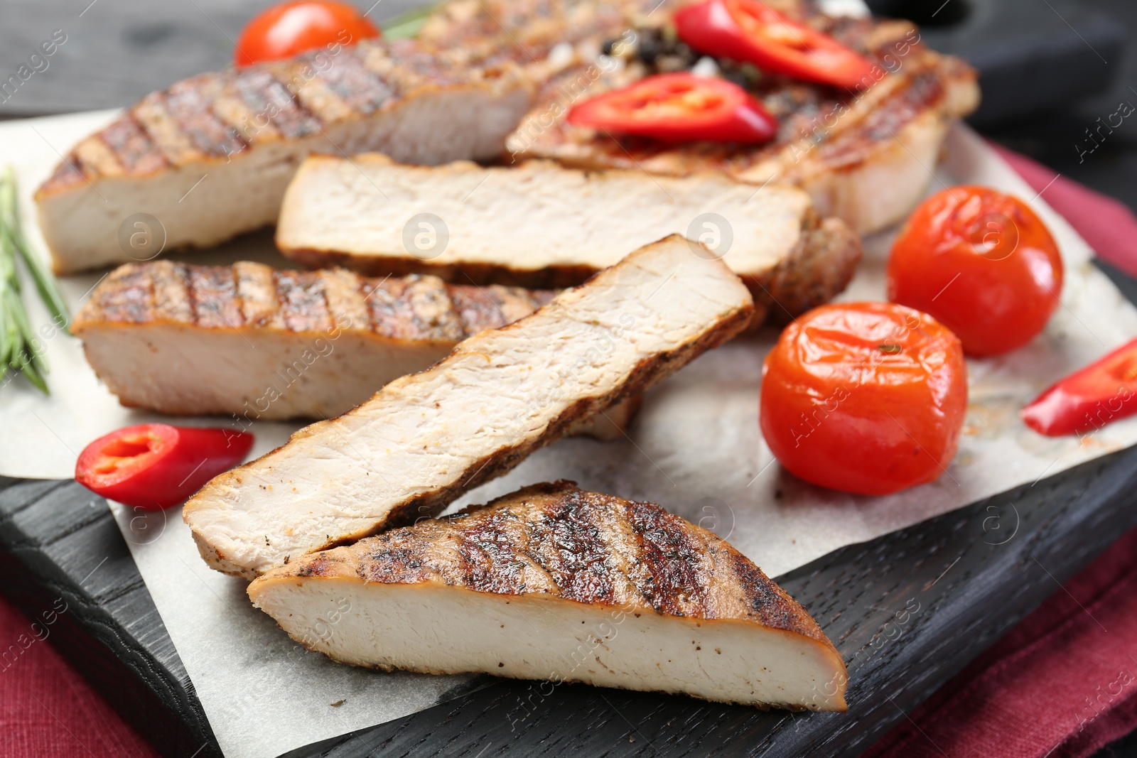 Photo of Cut grilled pork steaks with vegetables on table, closeup